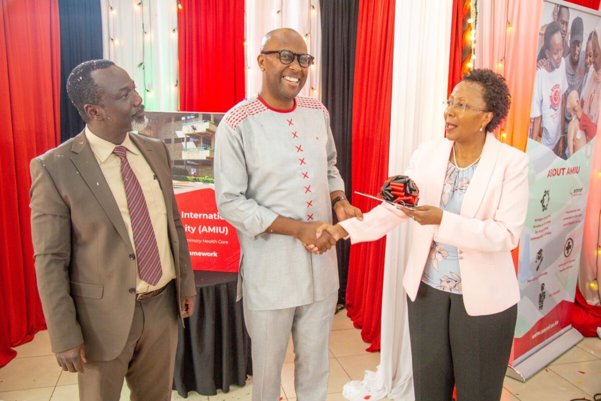 Muthoni Kuria, the University Council Chair, AMIU, gifting Dr. Gitahi with a copy of the Strategic Pan as Prof. Osur looks on. PHOTO/AMIU.