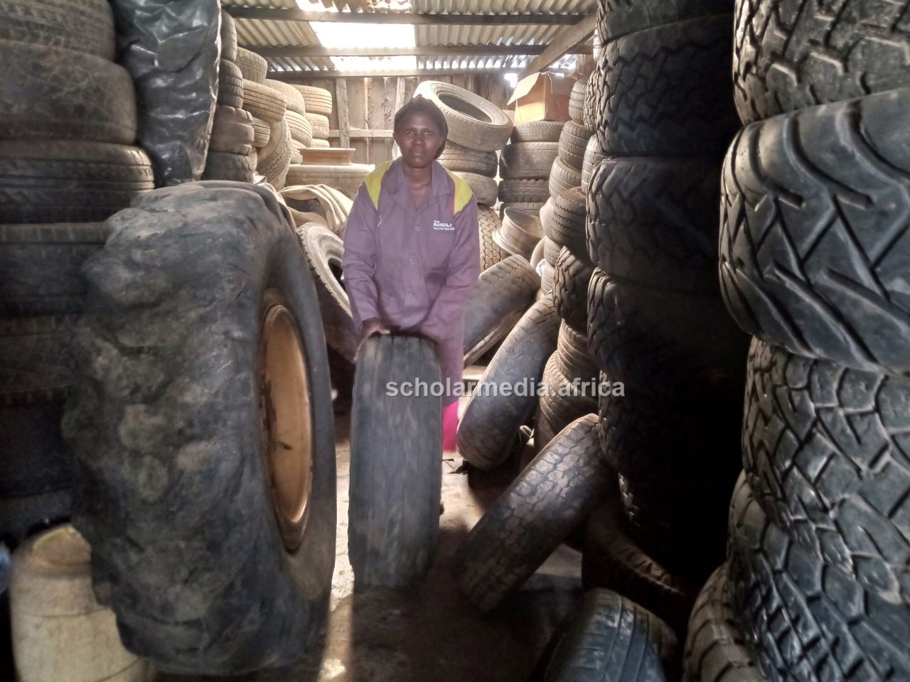 Nzisa at the tyre store. She has mastered the art of repairing old tyres for re-selling. PHOTO/Janet Kiriswo, Scholar Media Africa.