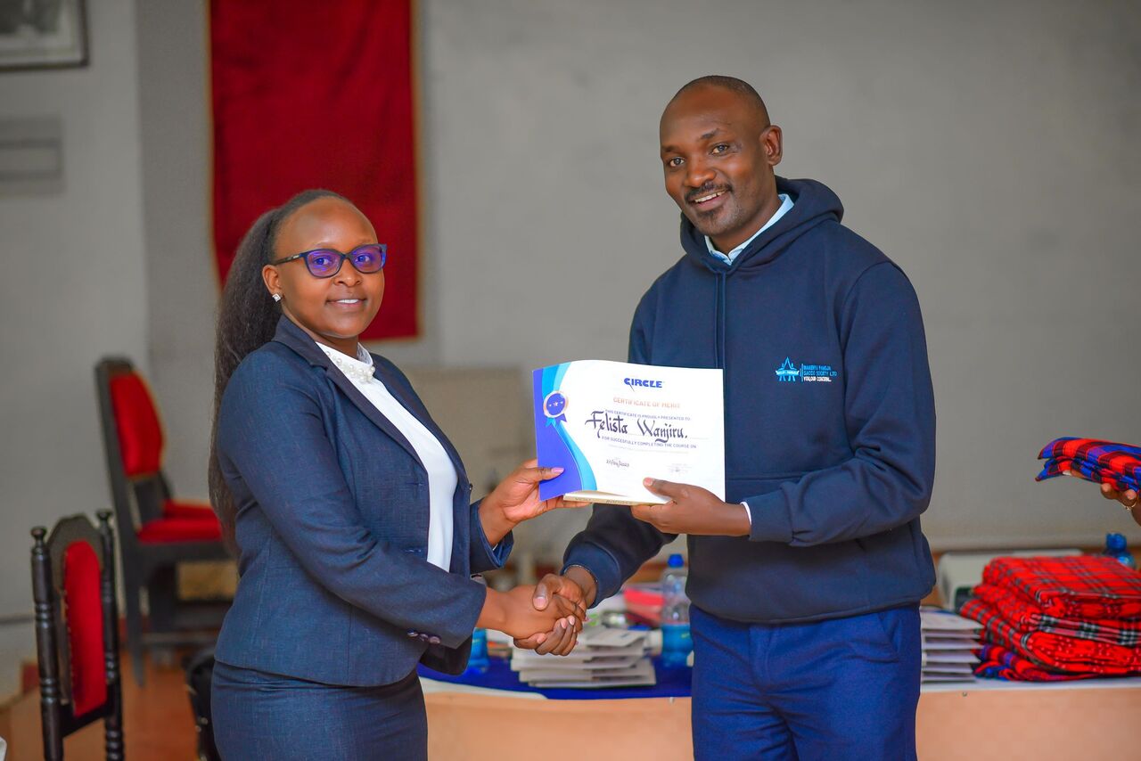 Felista Wanjiru, one of the training participants, being certified and gifted by Ronald Manyasia, the Operations Manager. PHOTO/Arise Circle.