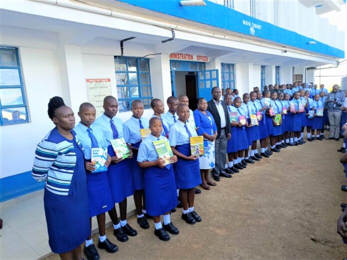 Top students showcase their revision books after getting awarded. With them are Mrs. Rebecca Ondicho (in front), Deputy Principal Administration, Mrs. Jane Nyanumba, Principal (center), BoM Chair, Dr. Charles Nyandusi (next to principal) and a teacher (far end). PHOTO/Tombe Girls.