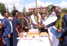 Invited guests and a section of the school management join Chief Principal Albert Ombiro (right) in cake cutting during thanksgiving on May 26, 2023, at Cardinal Otunga High School grounds. PHOTO/Boaz Khuteka, Scholar Media Africa.