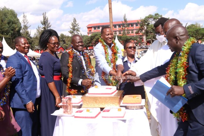 Invited guests and a section of the school management join Chief Principal Albert Ombiro (right) in cake cutting during thanksgiving on May 26, 2023, at Cardinal Otunga High School grounds. PHOTO/Boaz Khuteka, Scholar Media Africa.