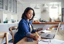 Young woman taking notes while going through paperwork in her remote-work schedule. Africa's future of work is taking shape towards innovation, remote jobs and tech-backed approaches. PHOTO/techcabal.