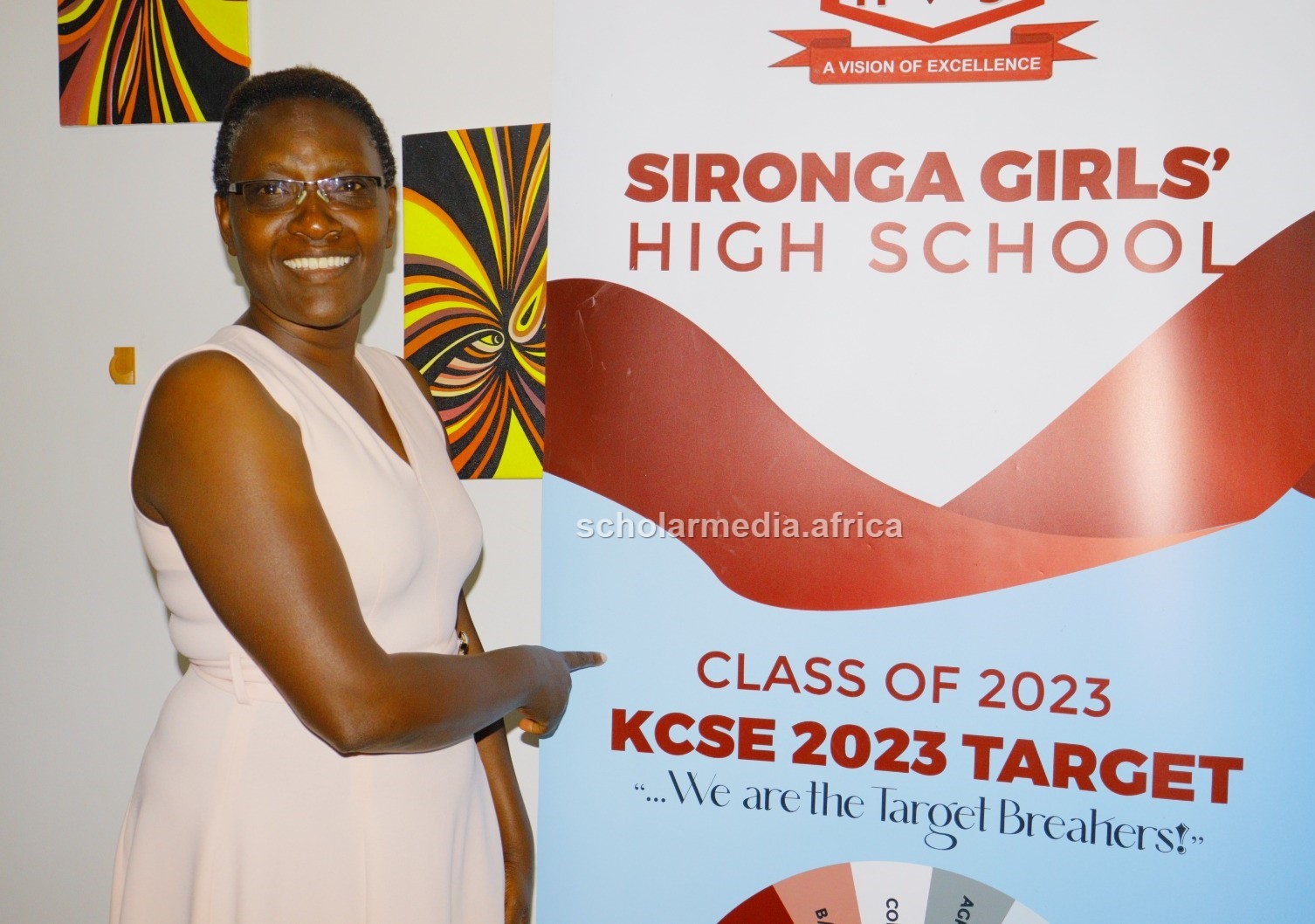 Dr. Omari stands beside the school's 2023 target mean banner. PHOTO/Josephat Nehemiah, Scholar Media Africa. 