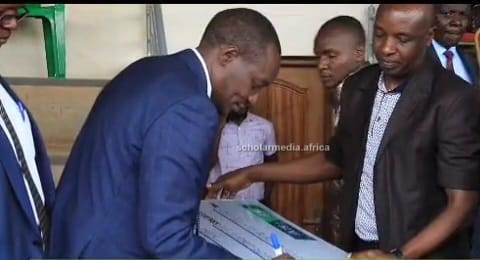 Governor Arati signs the bursary cheque. PHOTO/Samuel Okerosi, Scholar Media Africa.